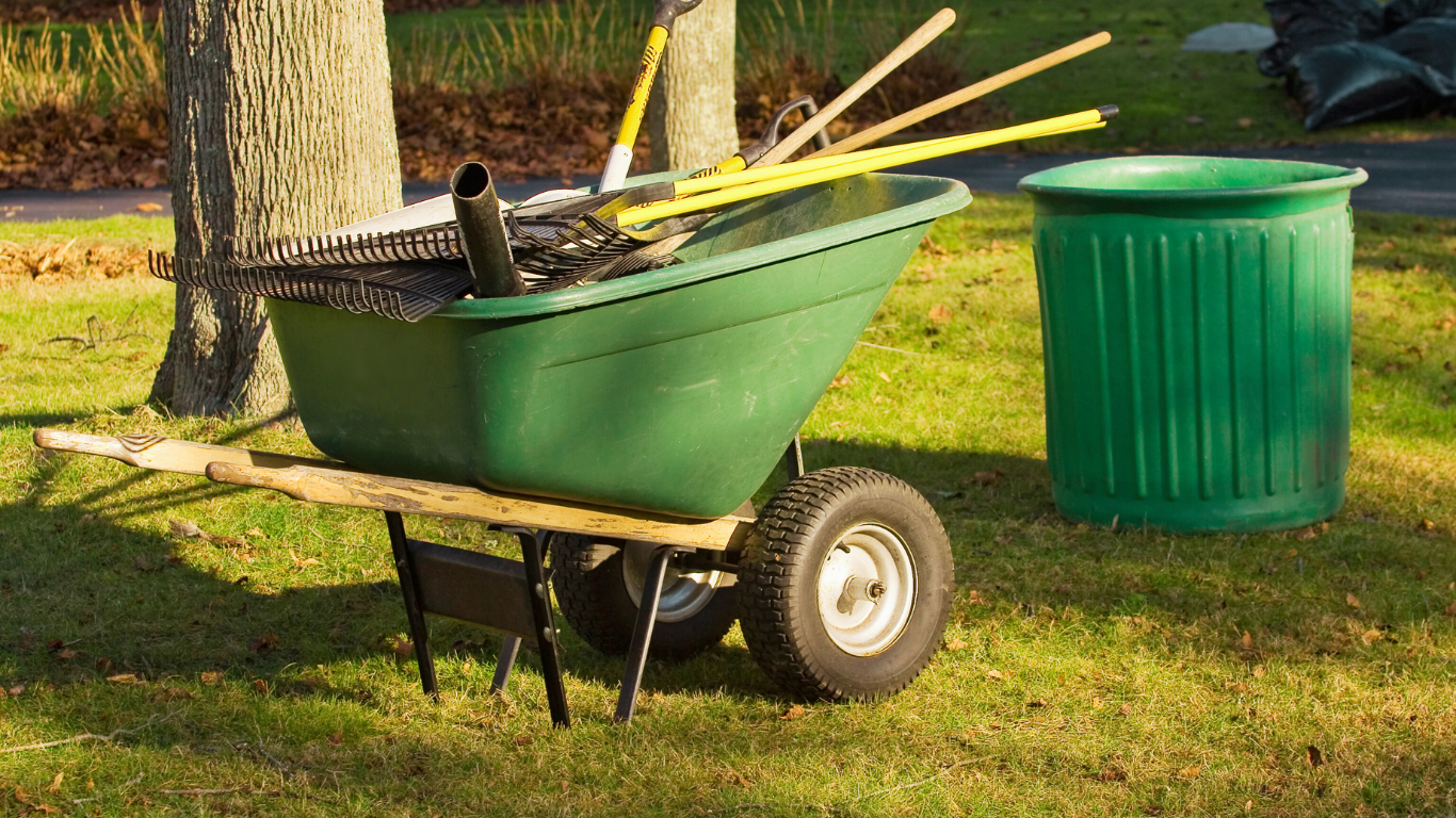 A wheelbarrow with cleaning tools and a trash bin, illustrating the importance of professional animal waste cleanup in Fort Myers for safe and efficient removal.
