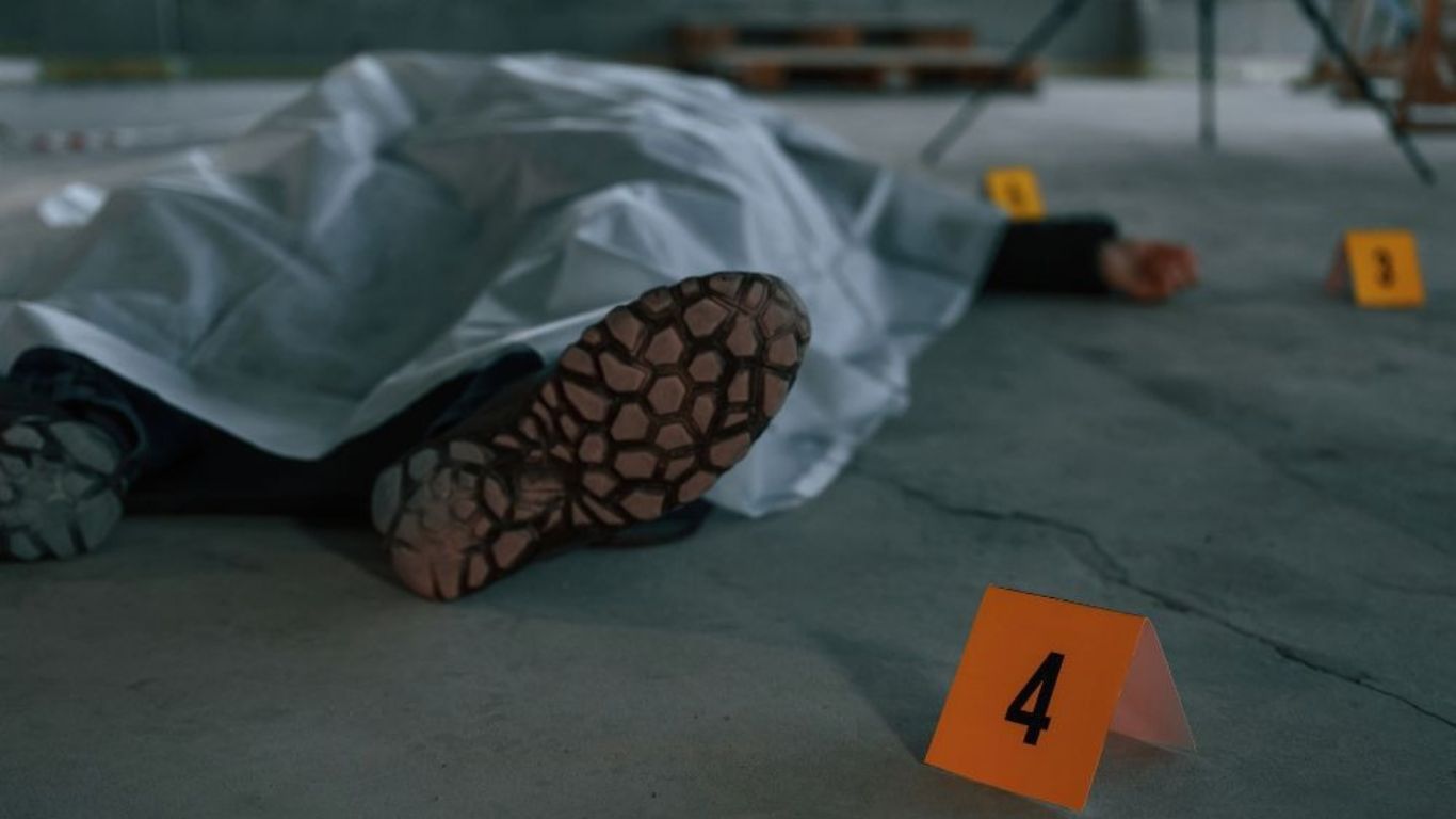 Crime scene with covered body and evidence markers for unattended death cleanup.